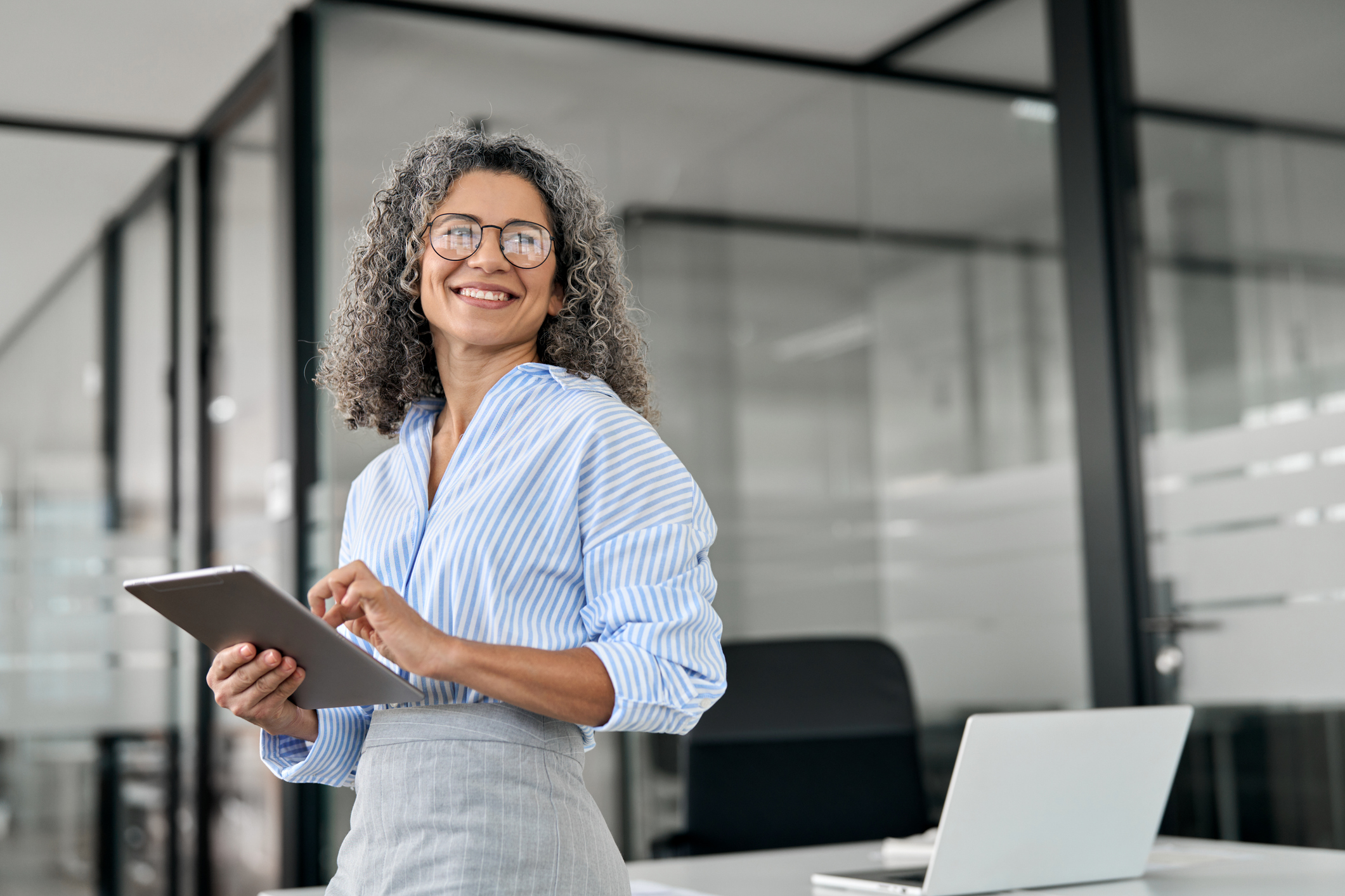 Experienced legal executive holding a tablet in a modern office