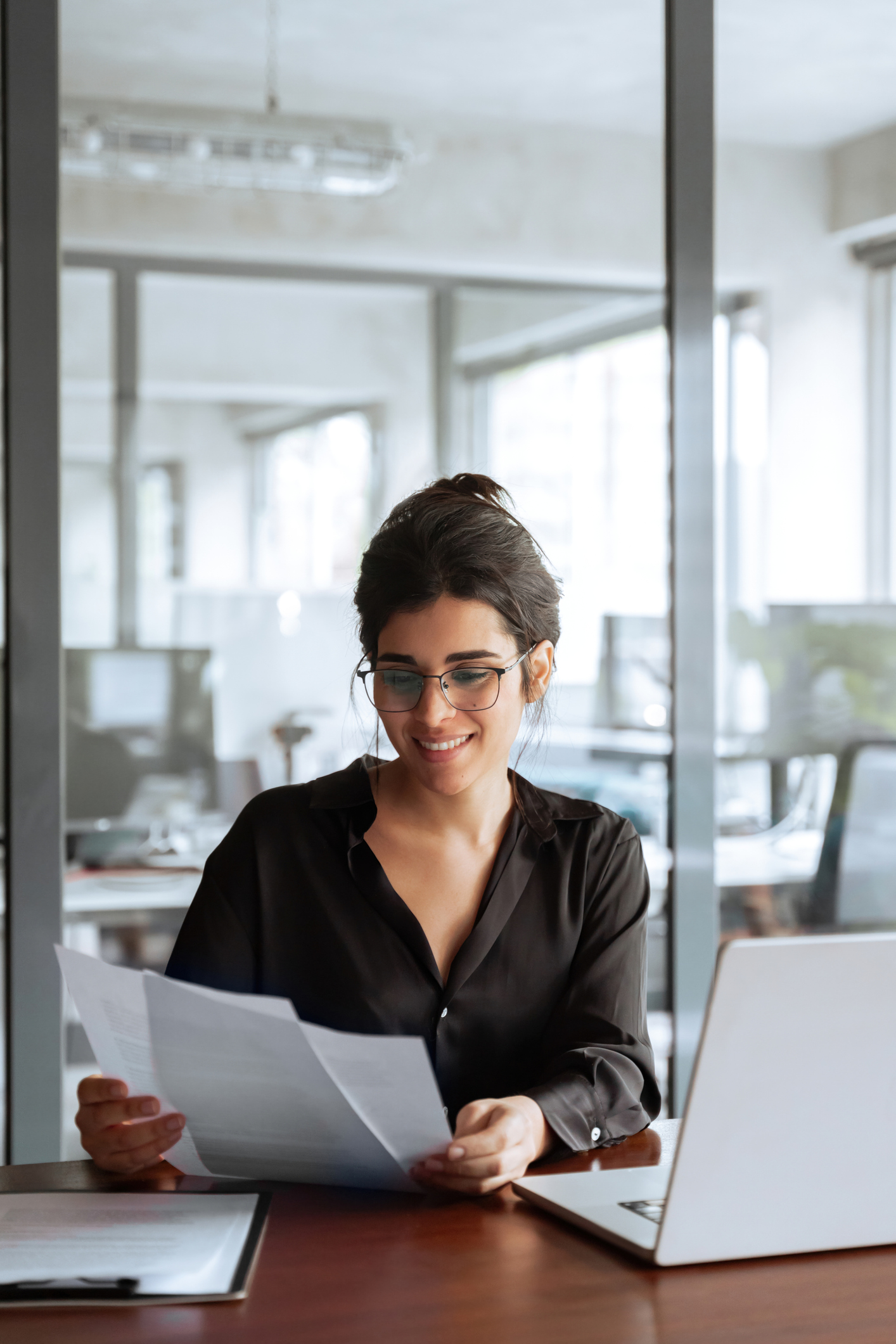 Corporate paralegal reviewing business documents at a laptop