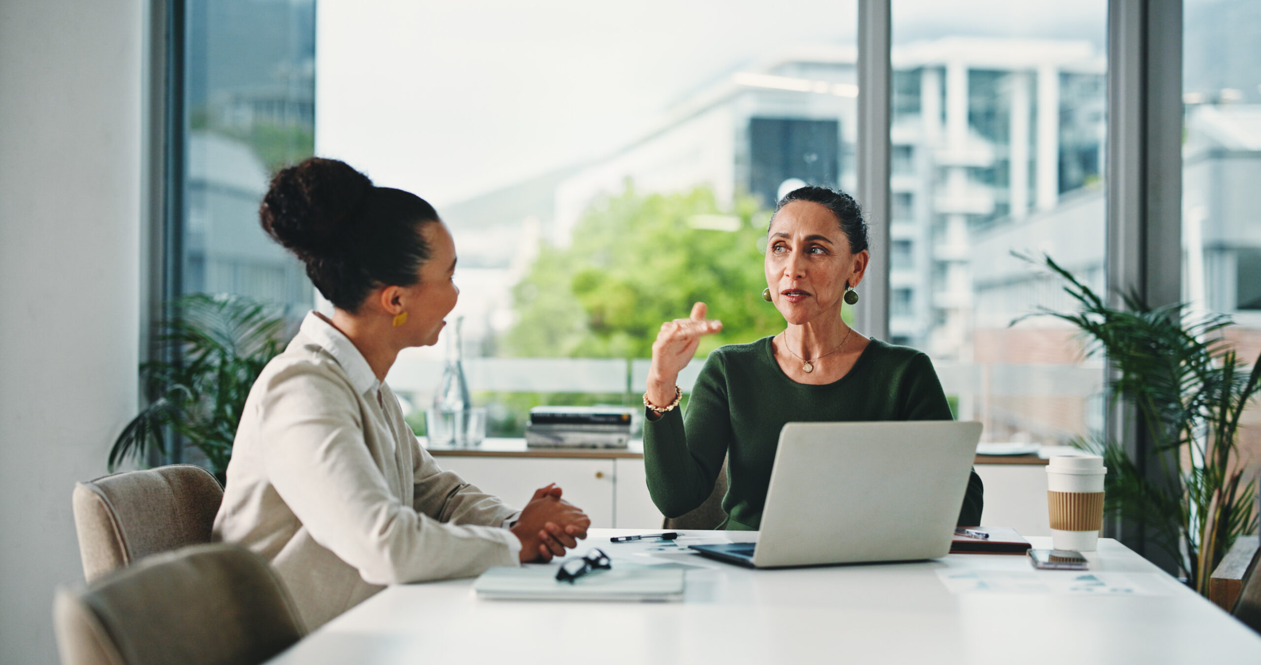 Two attorneys discussing legal work at a table with a laptop