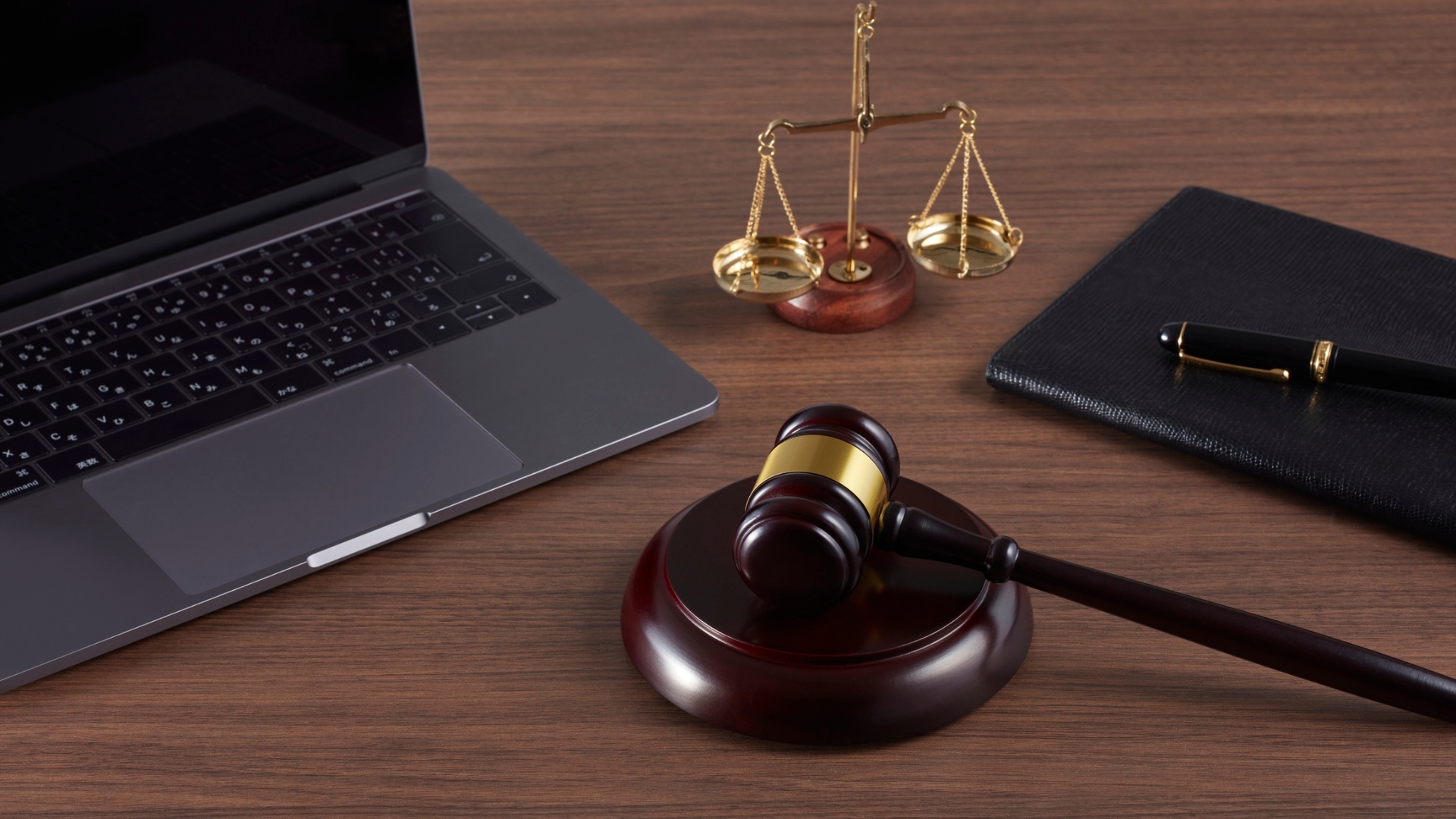 Laptop, notebook, scales, and gavel on a legal office desk