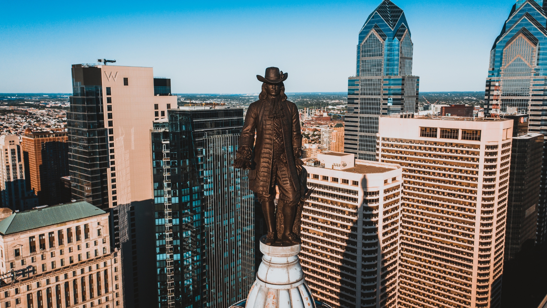 Bronze statue above downtown Philadelphia with surrounding buildings